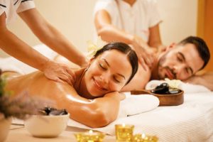 Young couple enjoying in back massage at health spa. Focus is on smiling woman.